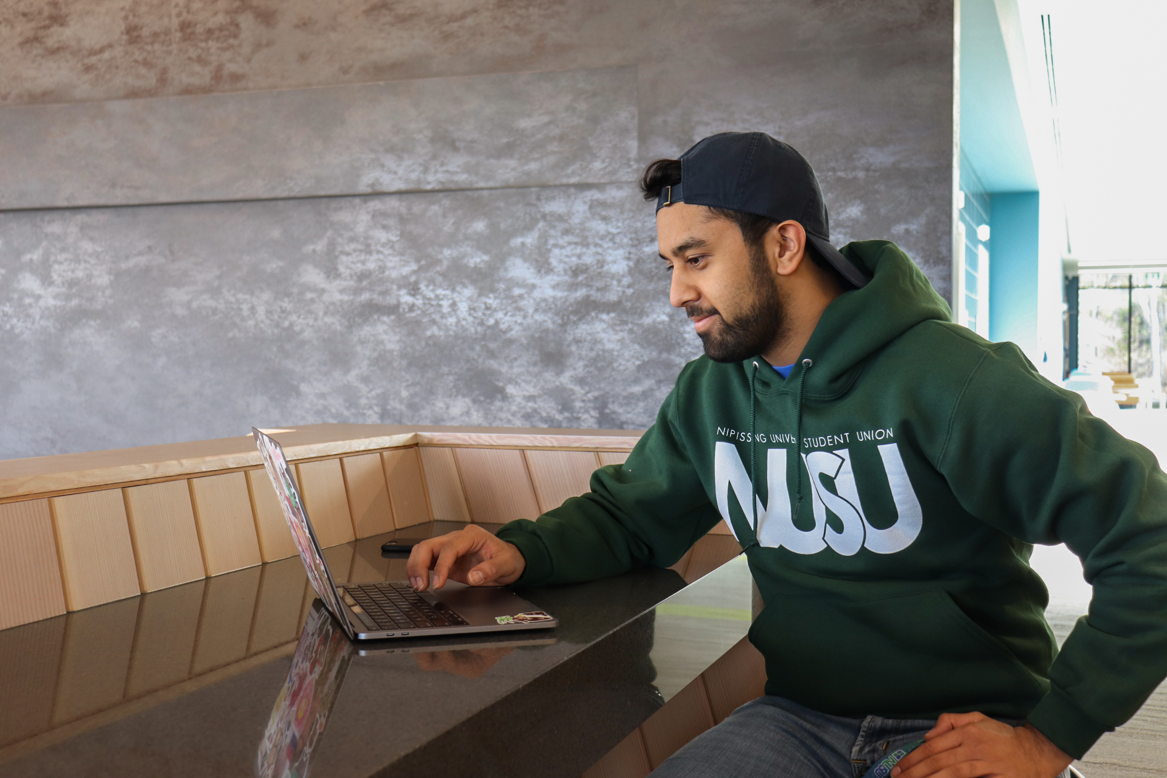 Student wearing a NUSU Hoodie Sweater in Forest Green